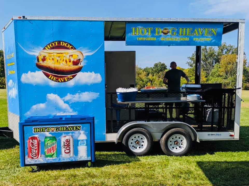 Hot dog food truck in sunny park.