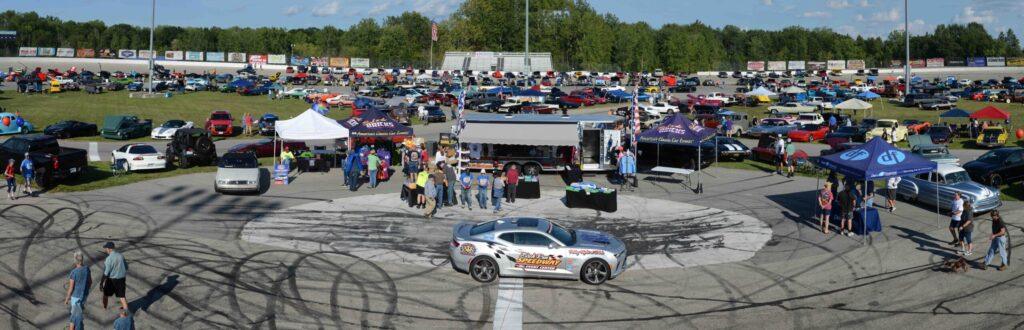A police car performing donuts with tire marks on the pavement at a crowded outdoor event.
