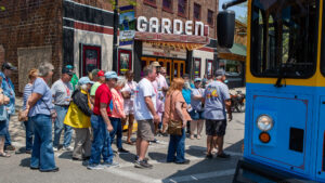 People waiting in line outside a venue with a 'Garden' sign.