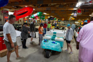 People explore a colorful indoor model boat exhibition under wooden beams.