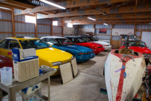 A row of colorful classic cars parked inside a wooden garage.