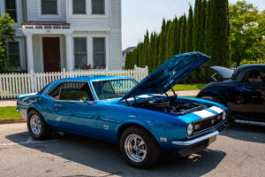 A blue classic muscle car with its hood open on display.