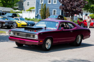 A classic maroon muscle car parked on a sunny suburban street.