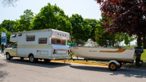 A camper trailer hitched to a boat on a sunny day.