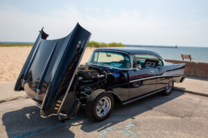 Classic black car with its hood open on a sunny day.
