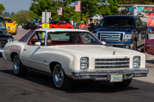 Classic white muscle car parked at an outdoor event.