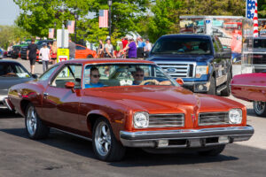 Classic red convertible driving in a parade with spectators in the background.
