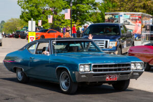 Classic blue muscle car cruising on a sunny day.