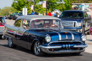 Classic black vintage car driving on a sunny day.