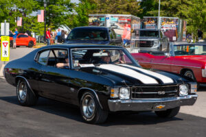 A classic black muscle car parked at an outdoor event.
