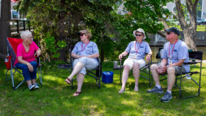 Two elderly women sitting outdoors on chairs, enjoying a sunny day.