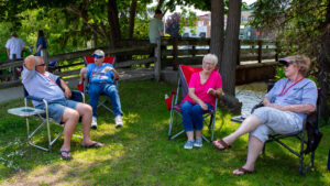 People relaxing outdoors on lawn chairs in a sunny park.