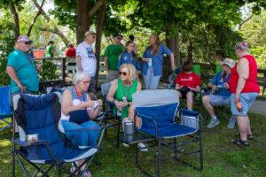 Group of people relaxing outdoors on a sunny day with trees in the background.