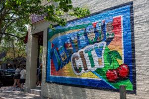 Colorful mural reading "Cherry City" with cherries on a brick wall.