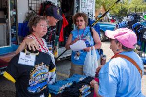 Volunteers engaging with a child at an outdoor event booth.