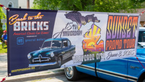 Banner celebrating Traverse City's 75th anniversary with classic car and bat images.