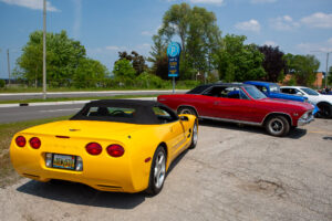 A yellow convertible sports car and a red classic car parked outdoors.