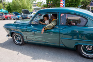 People enjoying a ride in a vintage car during a sunny day.