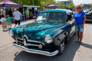 A shiny vintage teal car displayed at an outdoor event.