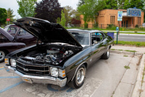 Classic black muscle car with its hood open, showcasing the engine.