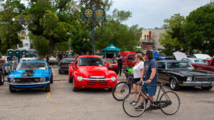 People enjoy a sunny day at a classic car show with vibrant vintage vehicles.
