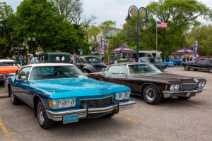 Two classic cars parked side by side at an outdoor event.