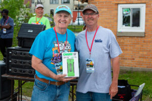 Two men smiling, one holding a prize box outdoors.
