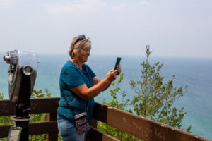 Woman taking a photo with her phone near the sea.