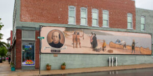 Mural of Joseph Smith with historical figures and symbols on a brick wall.