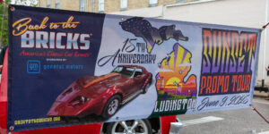 Banner celebrating Ludington's 75th anniversary with a car and lighthouse.