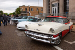 Classic cars parked on a wet street under cloudy skies.