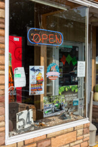 A storefront window with various colorful signs and an 'OPEN' neon sign.
