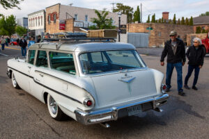 Classic white station wagon parked on a street with a man nearby.