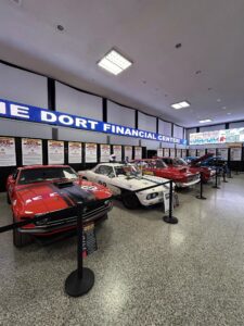 A row of classic cars displayed indoors with financial signage above.