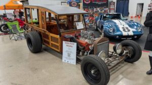 Classic woody hot rod car displayed indoors with vintage aesthetic.