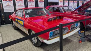 Classic red muscle car with racing decals on display.