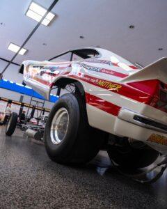 A racing car lifted on a platform in a garage or workshop.