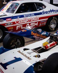 Classic racing cars from different eras parked together at a motorsport event.