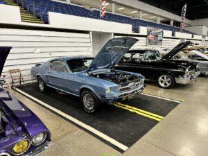 Classic blue American muscle cars parked indoors at a show.