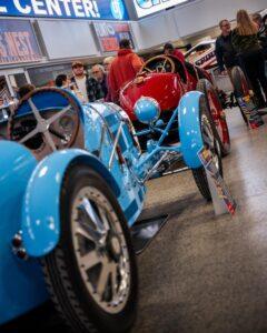 A line of vintage cars in a garage or workshop setting.