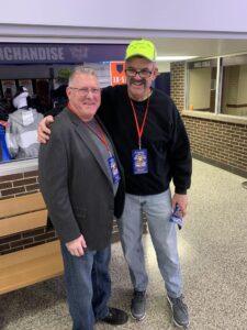 Two men smiling and posing for a photo indoors at an event.