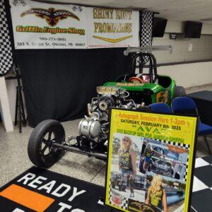 A green dragster car on display at an indoor event.
