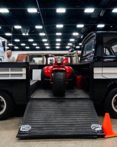 A red motorbike parked inside a truck bed with a ramp below.