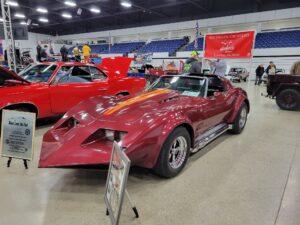 Custom red sports car with unique design at an indoor car show.