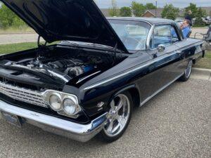 Classic black vintage car with hood open, showcasing polished engine.