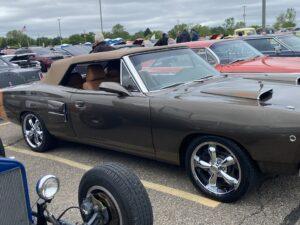Classic convertible car with shiny chrome wheels at a car show.