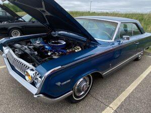 Classic blue vintage car with hood open showing engine.