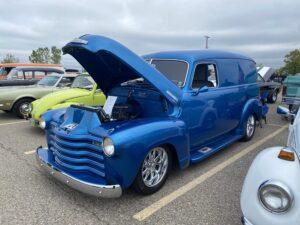 Classic blue vintage car with hood open at a car show.
