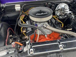 Close-up of a classic car engine with Edelbrock air filter and polished components.