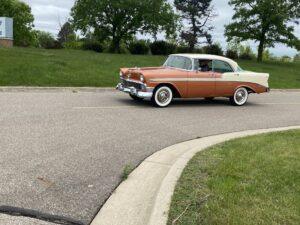 Classic orange and white vintage car parked on a suburban street.